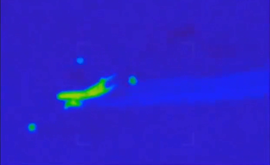 Drone FLIR-style still showing three orb-like objects around the airliner-like target